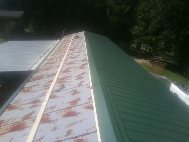 Old rusted panels beside newly installed green metal roofing — Wind Damage Roof Repair by Roofing Brothers in Springboro