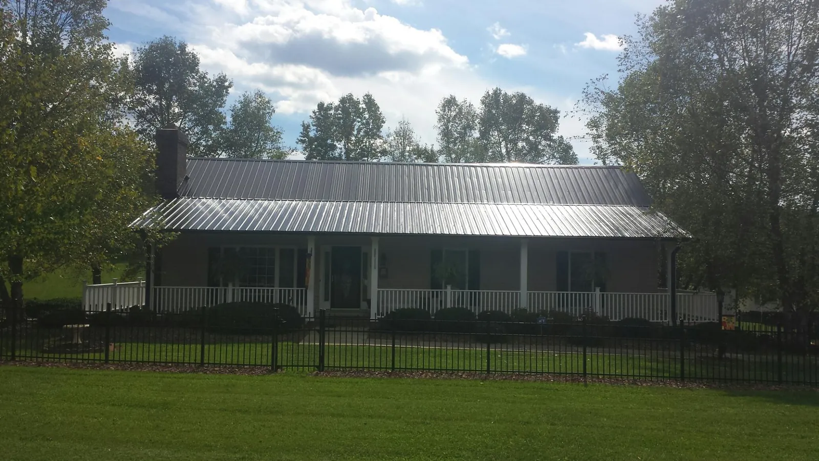 Gray metal roof on a brick ranch with a full width front porch — Gutter Guard Installation work by our crew in Springboro